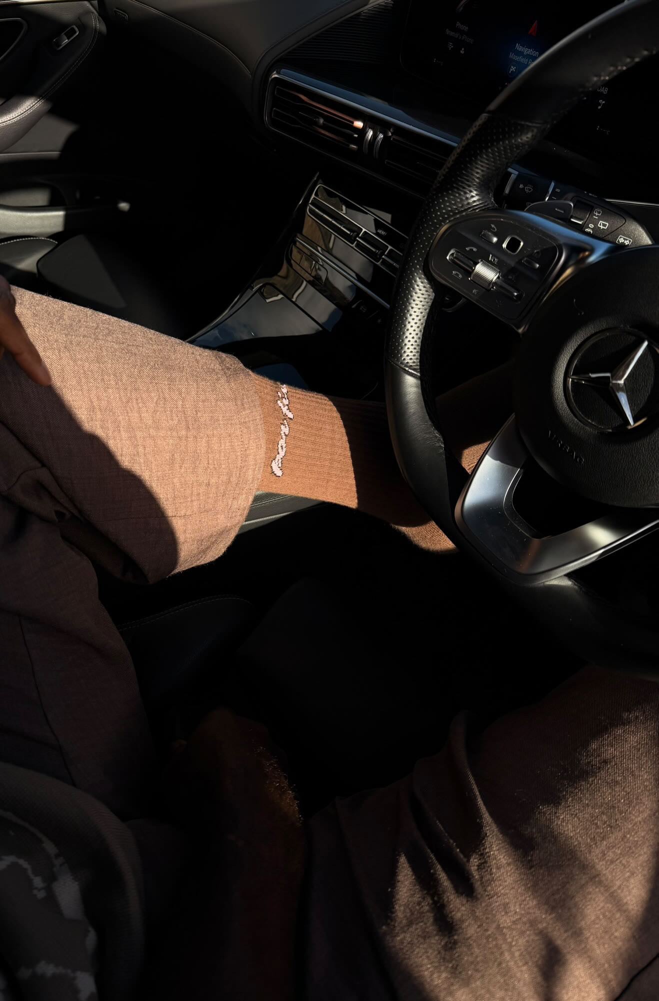 Person sitting inside a car with a focus on the socks.